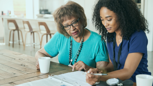 An image of two individuals filling out insurance paperwork